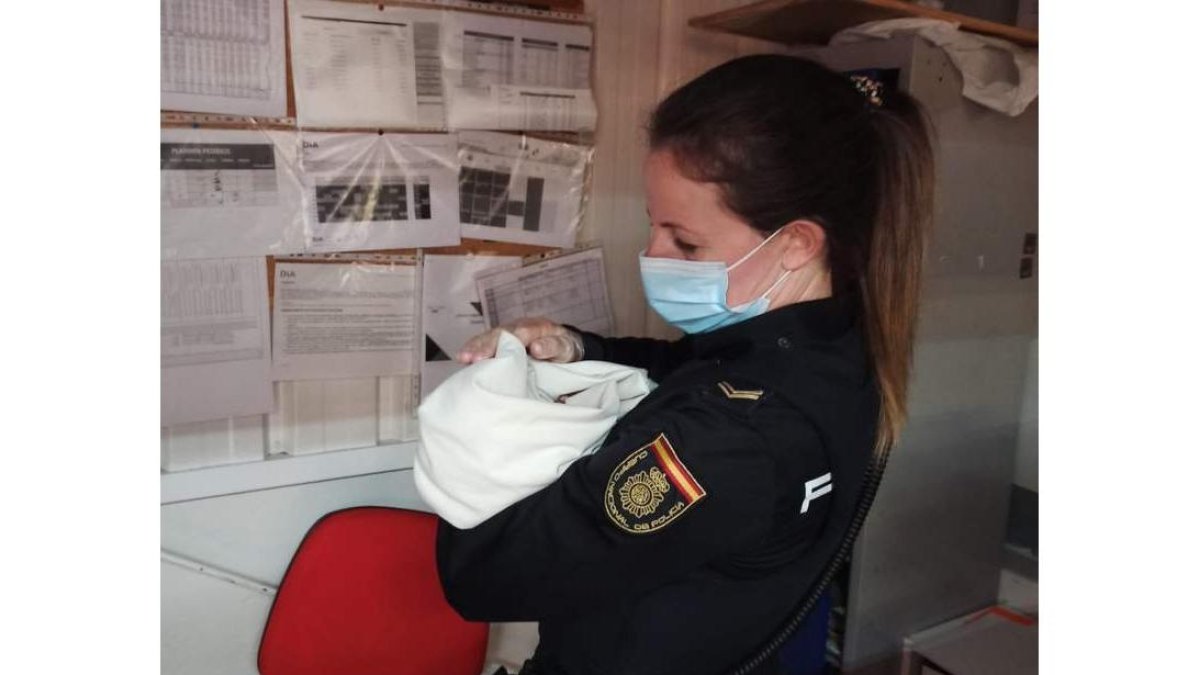 Una agente de la Policía Nacional sostiene en brazos al bebé encontrado en el súper. POLICÍA NACIONAL