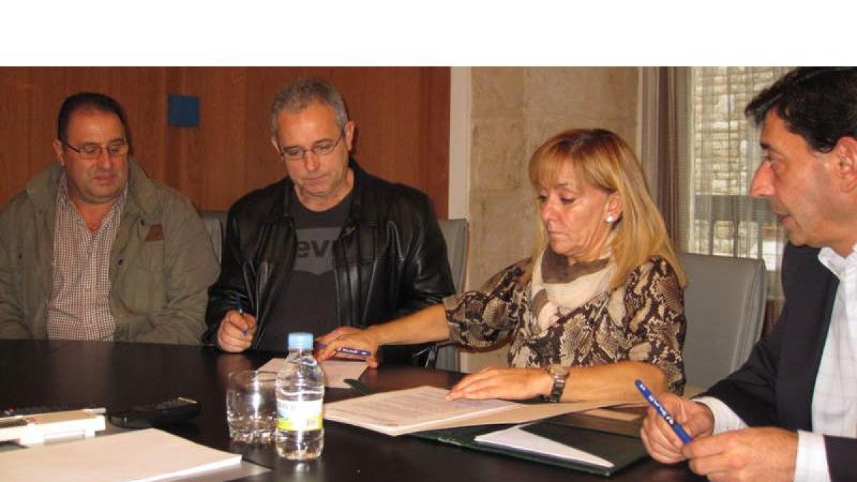 Olano y Carrasco, en el centro, firmando el convenio.