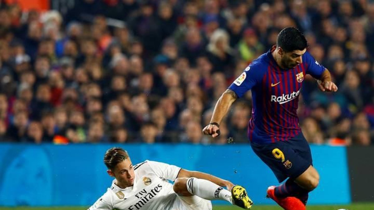 El delantero uruguayo del FC Barcelona, Luis Suárez, se lleva el balón ante el centrocampista del Real Madrid, Marcos Llorente.