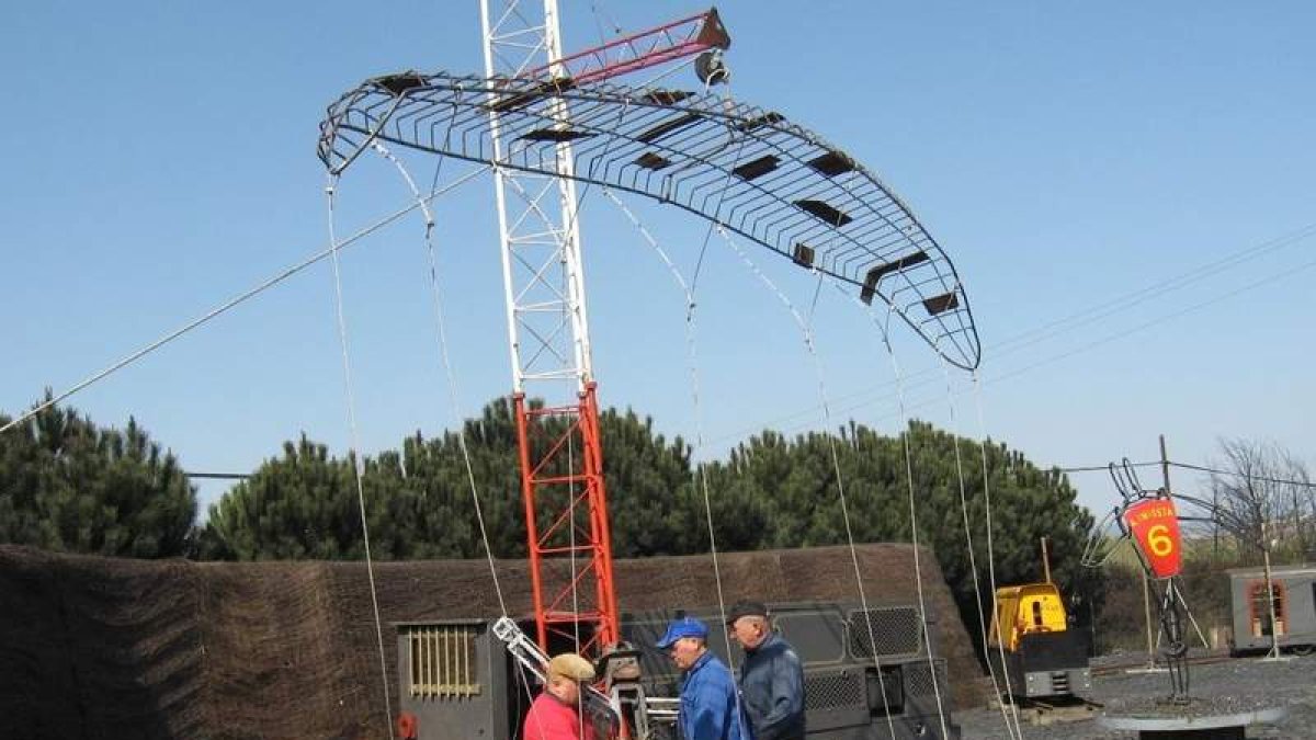 Tres jubilados hacen pruebas con la estatua del minero con parapente metálico aún sin terminar.