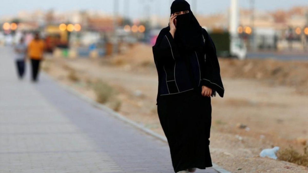Una mujer saudi habla por teléfono mientras camina por una calle de Riad