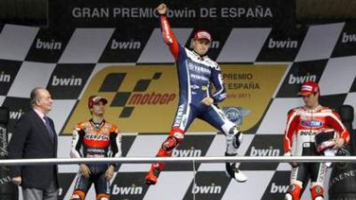 El rey Juan Carlos observa al piloto Jorge Lorenzo, que celebra en el podio la victoria conseguida.