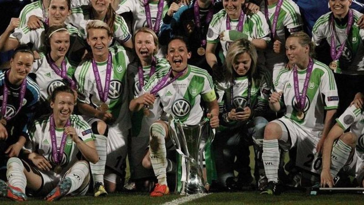 Las jugadoras del Wolfsburgo posan sobre el cédped con el trofeo de campeonas de Europa.