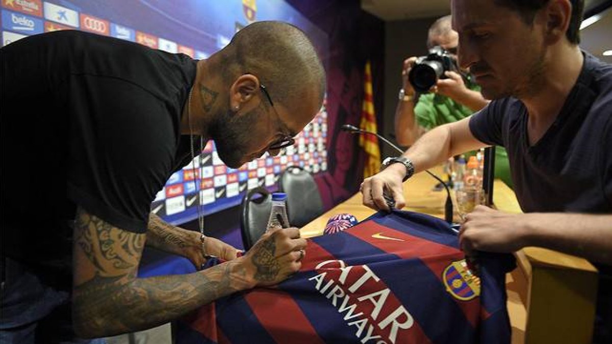 Dani Alves firma una camiseta antes de su comparecencia.