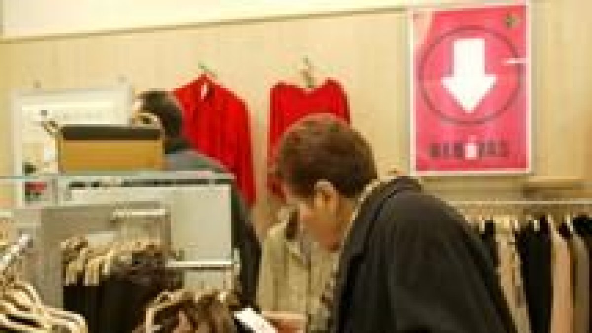 Una mujer observa atentamente la etiqueta de una prenda durante el primer día de rebajas