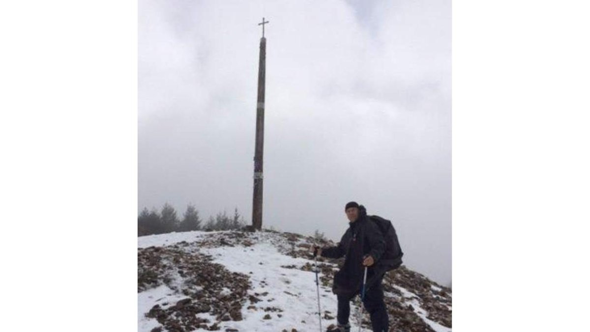 Marco posa a los pies de la Cruz de Ferro y Laura camina sobre la nieve. WWW.2CUORINCAMMINO.IT