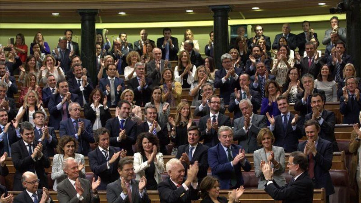 El líder del PP, Mariano Rajoy, aplaudido por todos sus compañeros en el momento en que el Congreso le dio por investido.