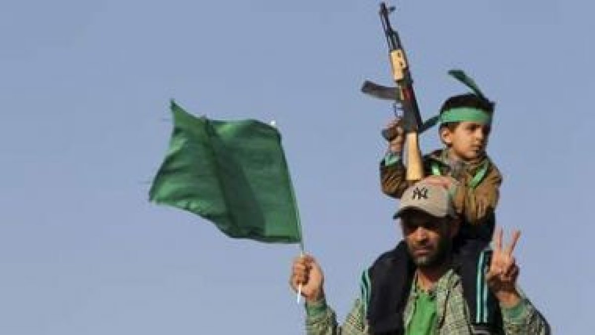 Un hombre libio carga a su hijo mientras ondea una bandera nacional.
