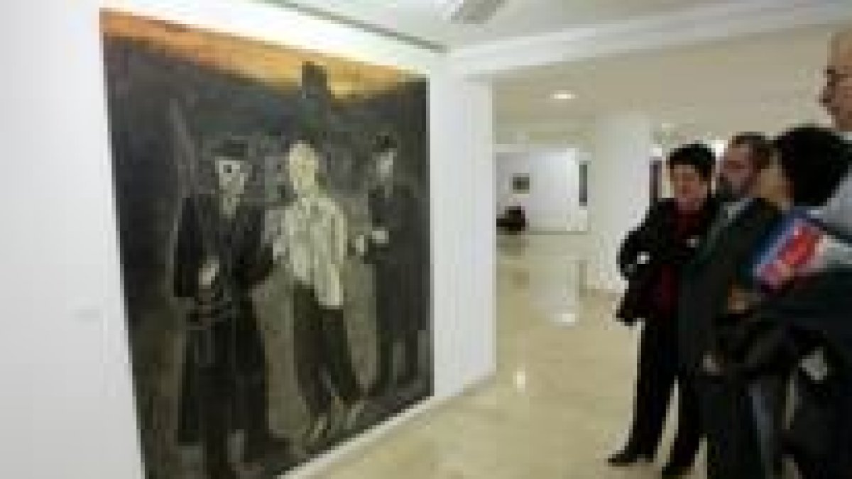 Los organizadores de la exposición admiran uno de los cuadros de la muestra