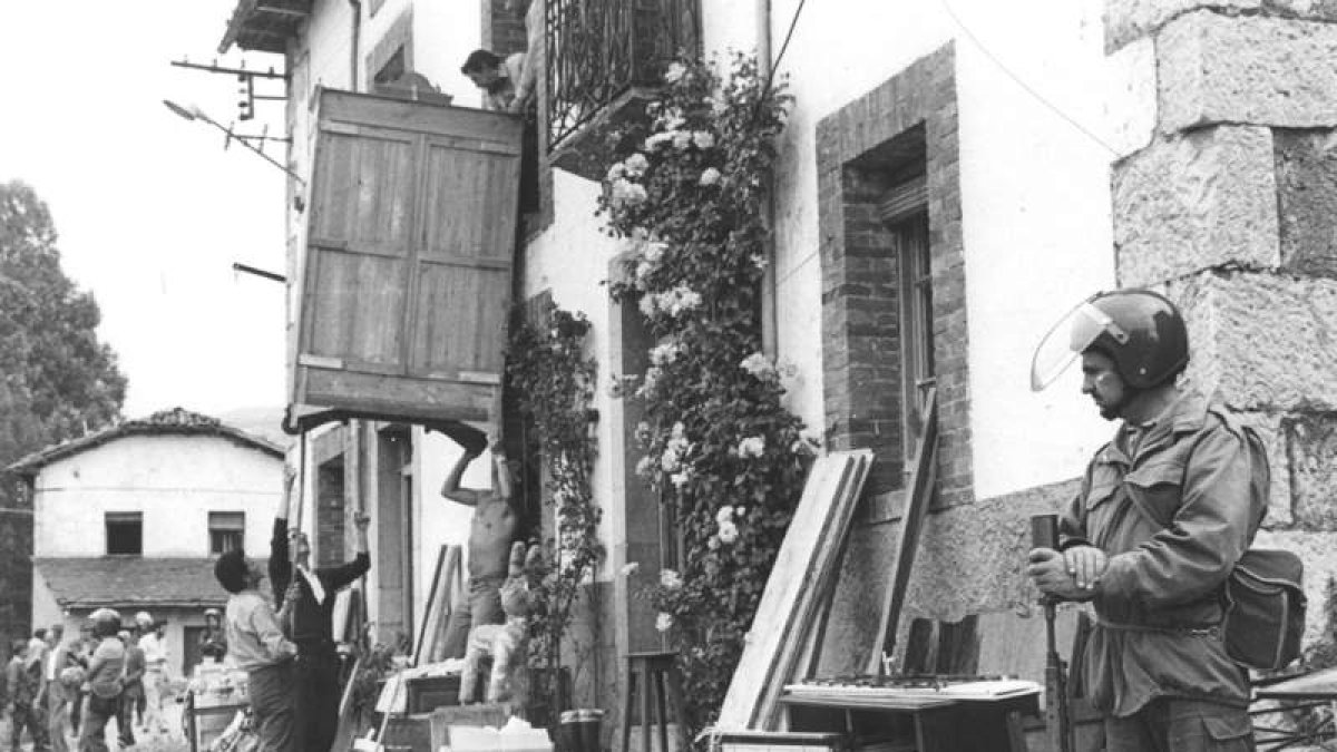 Un policía vigila mientras una familia desaloja los enseres de su vivienda, hace 30 años. CÉSAR