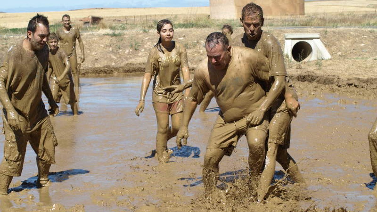 Los entregados deportistas se disputan el balón en un peculiar campo de fútbol-barro.