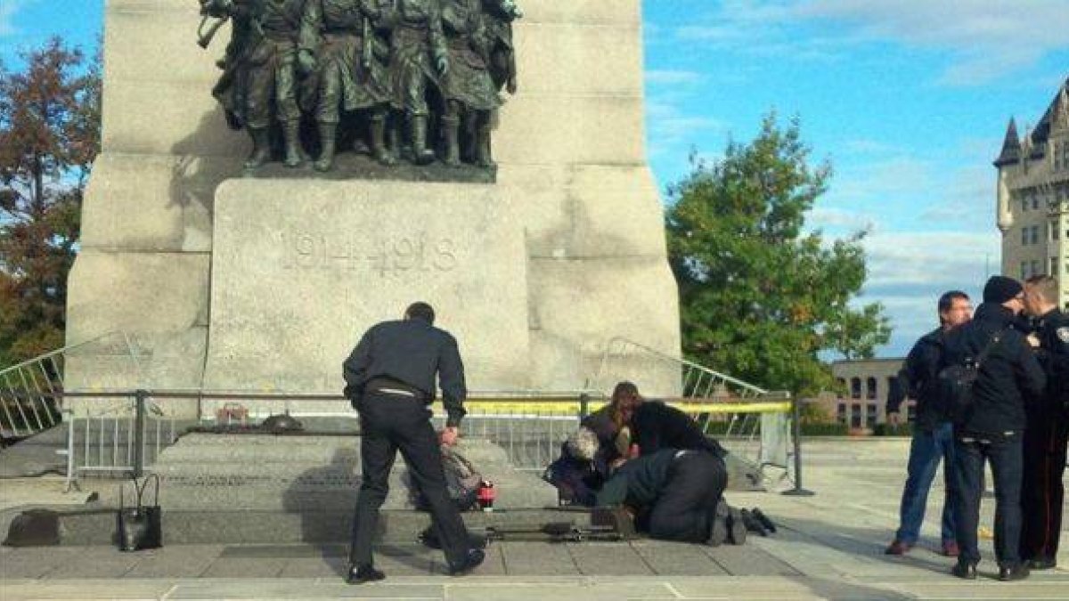Unos soldados atienden a un compañero herido, ante el monumento de los veteranos de guerra en Ottawa.