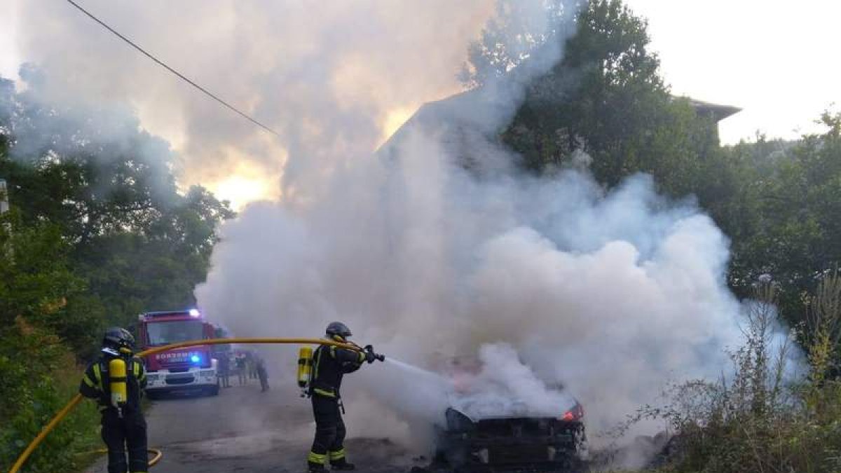 Los bomberos en plena operación para apagar el vehículo en Villanueva de Valdueza. DL