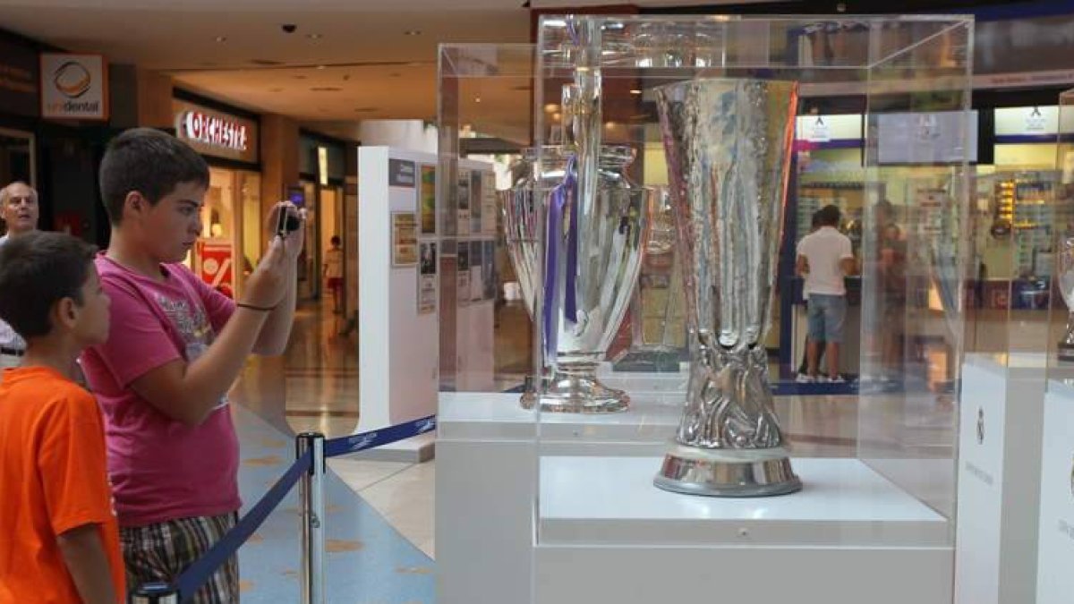 Dos jóvenes seguidores hacen fotos a las vitrinas donde están las copas.