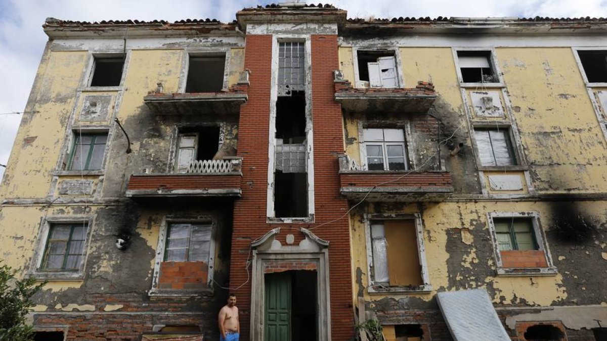 Uno de los habitantes del viejo edificio delante de la casa, que presenta un grave deterioro