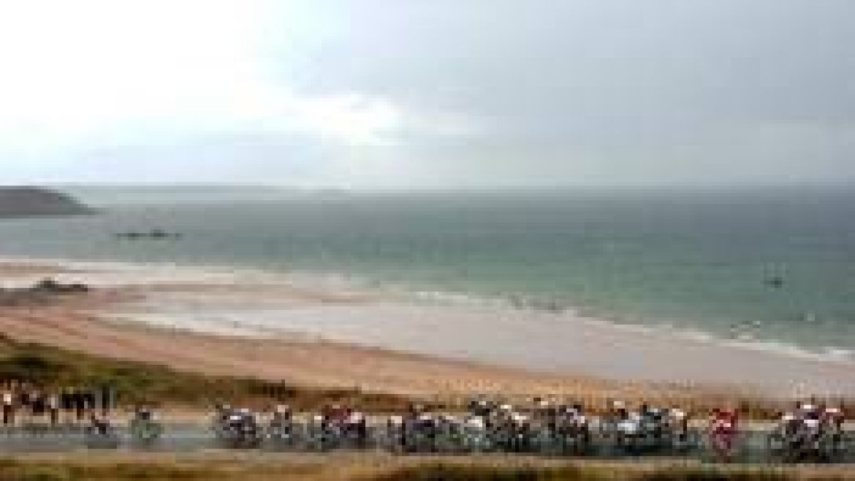 Los ciclistas pasan al lado del mar, con la playa como fondo testimonial