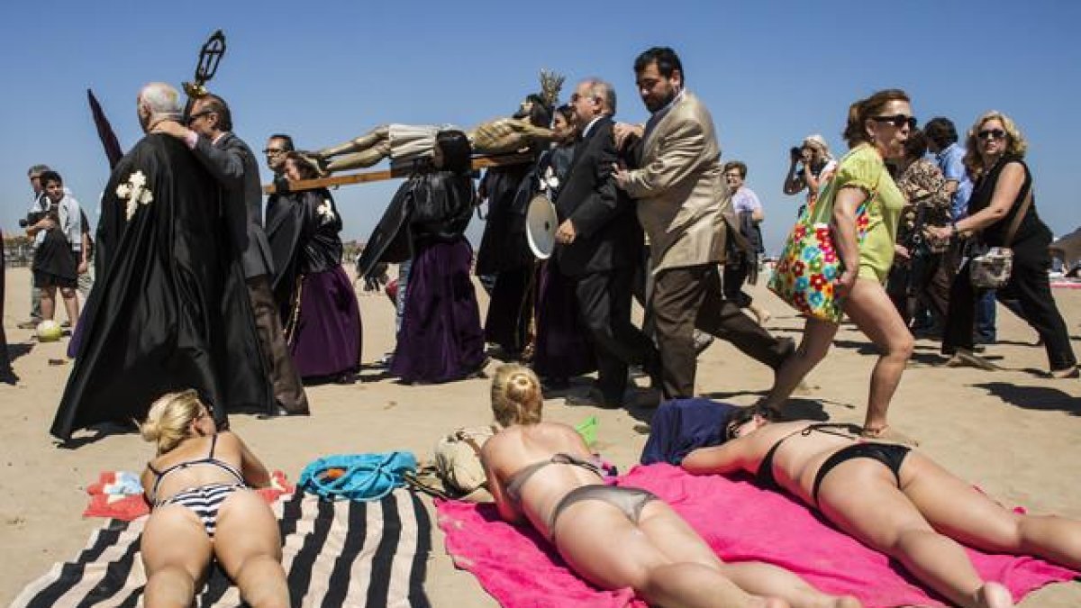 Bañistas y cofrades, en la playa de la Malvarrosa de Valencia, en la Semana Santa del 2014.