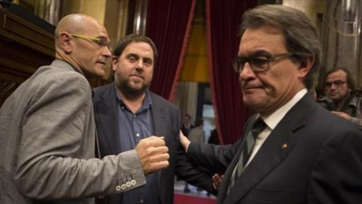 Raül Romeva, Oriol Junqueras y Artur Mas se saludan al terminar la sesión matinal del Parlament de ayer.