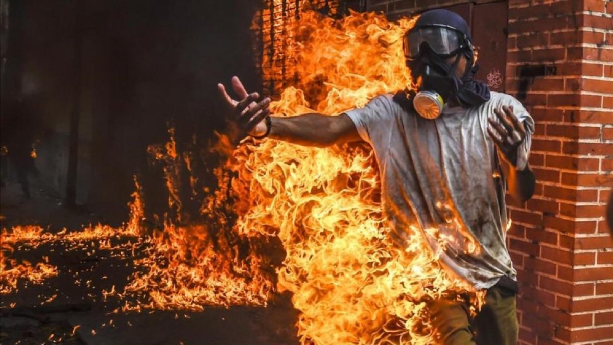 Un manifestante entre llamas después de estallar el depósito de la moto de un policía durante una protesta contra el presidente Maduro en Caracas.