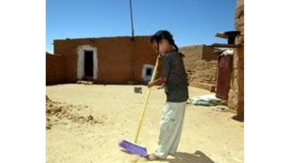 Una niña barre el patio de su casa
