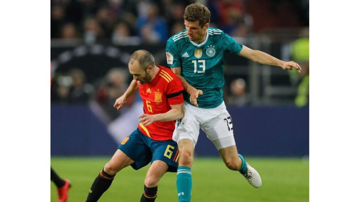 El fino futbolista de la selección española Andrés Iniesta se lleva el balón ante el alemán Thomas Müller. RONALD WITTEK