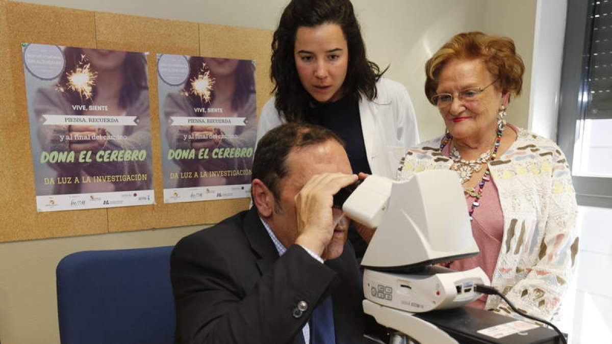 El consejero mira a través del microscopio cedido al Hospital por la Asociación de Alzhéimer de León. RAMIRO