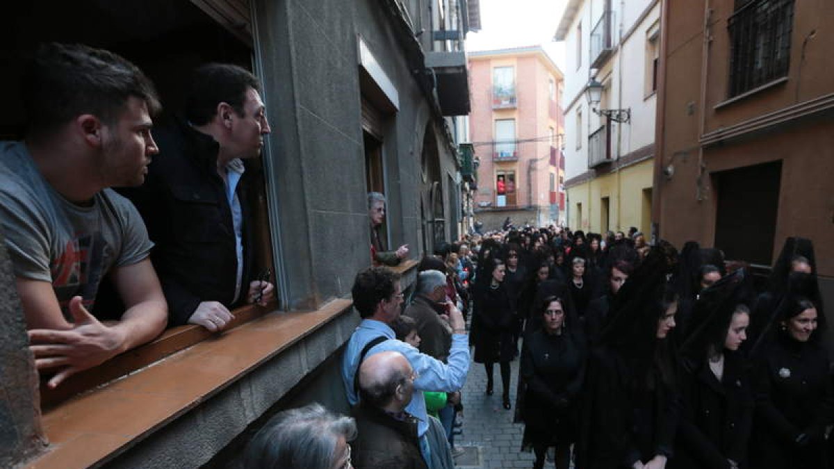 Varias personas ven pasar una de las muchas procesiones que transcurren por el casco viejo de la ciudad desde las ventanas de sus casas.