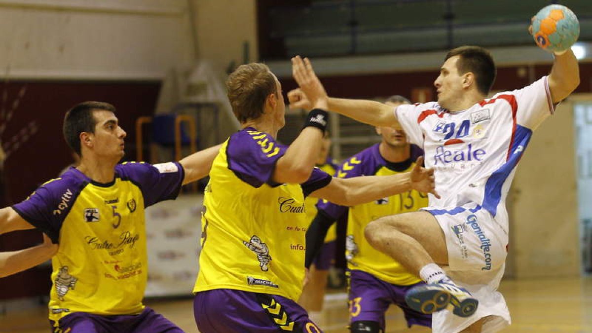 El lateral serbio Golubovic intenta un lanzamiento rodeado de jugadores del Balonmano Valladolid.