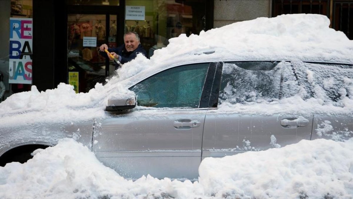 Un hombre limpia de nieve su coche atrapado por la nieve en una céntrica calle de Ávila, el pasado domingo.