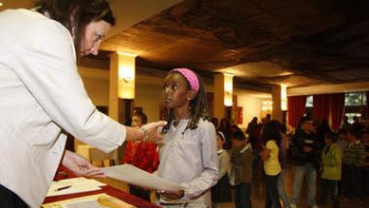 Una pequeña recoge el diploma que acredita su asistencia a los cursos.