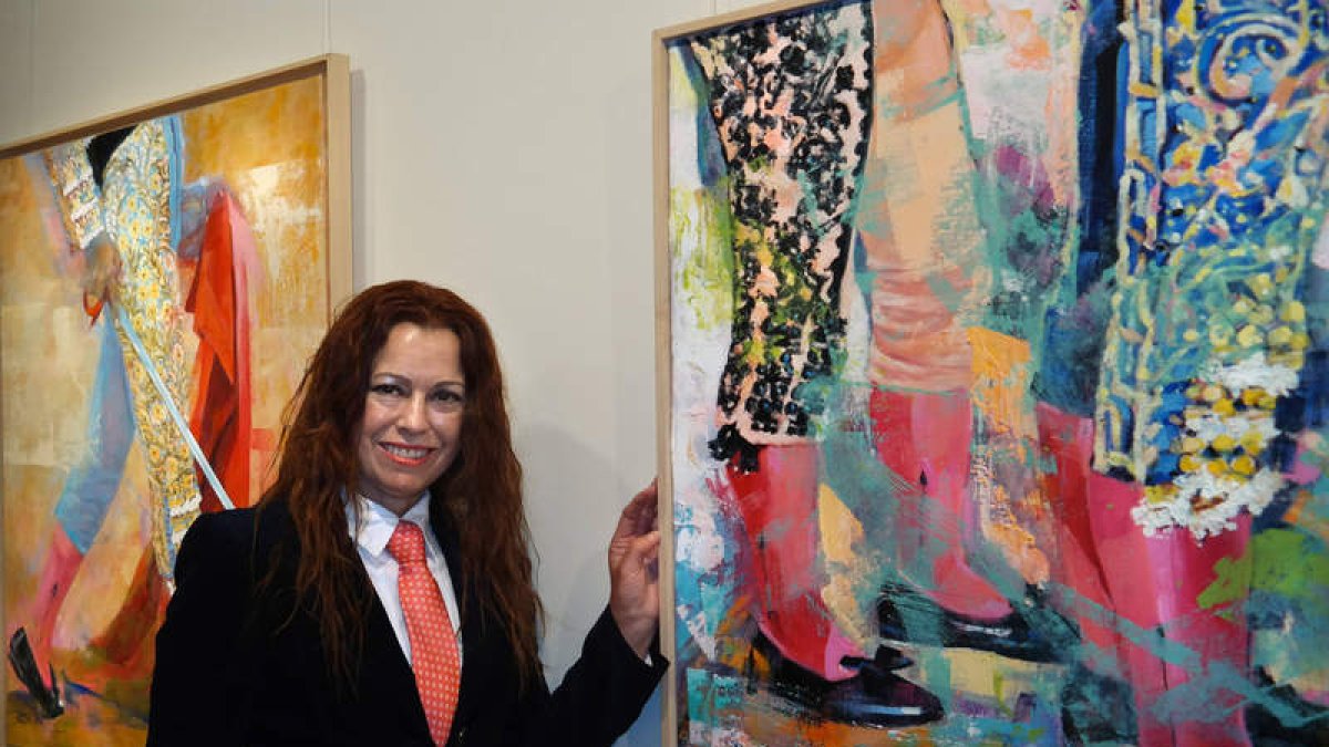 La artista onubense Carmen Gómez posa junto a dos de las obras de la exposición. CUEVAS
