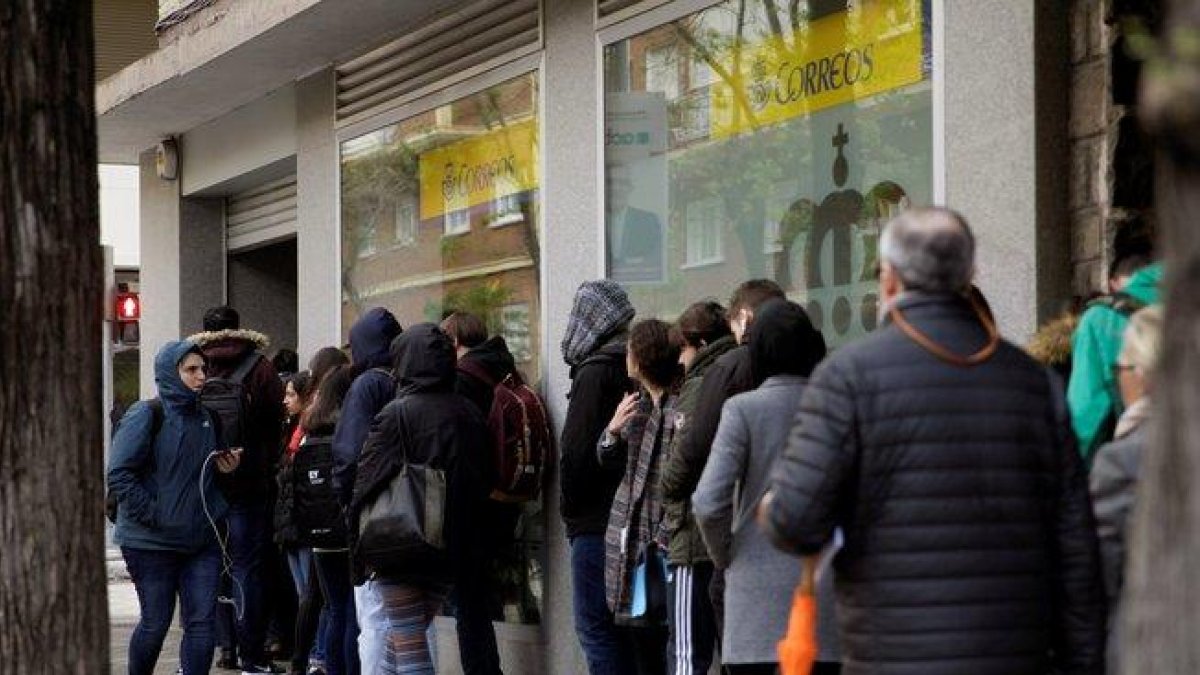 Decenas de personas hacen cola en una oficina de Correos para votar en las elecciones generales.