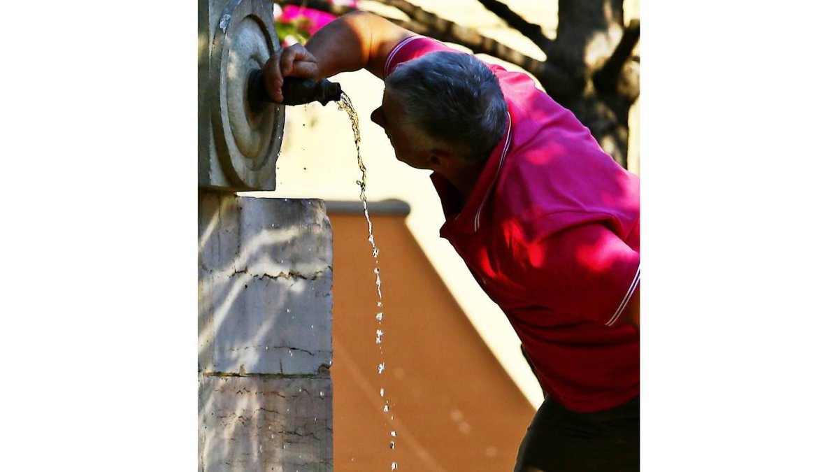 Un hombre se refresca en una fuente de León