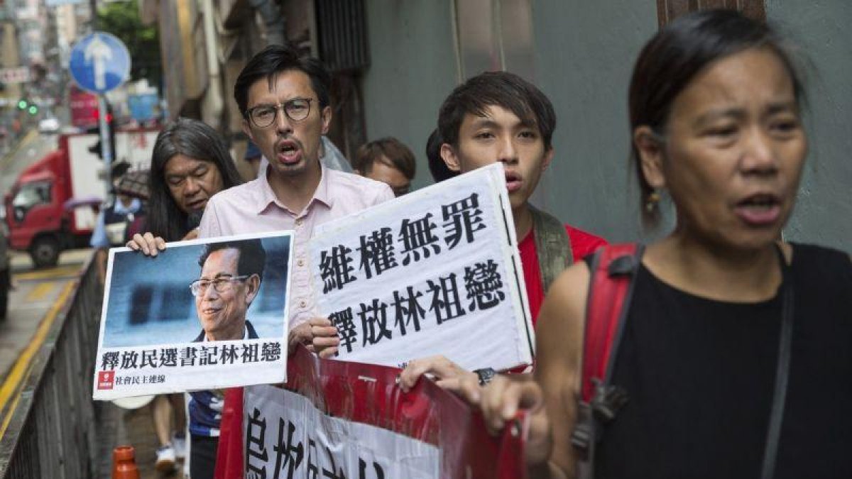 Varios seguidores del alcalde de la localidad meriodional de Wukan, Lin Zuluan, sostienen pancartas y protestan de camino a la oficina china Liaison en Hong Kong.
