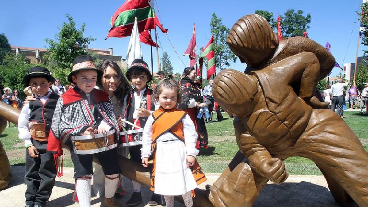 Jeanette Dayana Pérez posa con niños y niñas vestidos con trajes típicos leoneses junto a la escultura que homenajea al Pendón Leonés