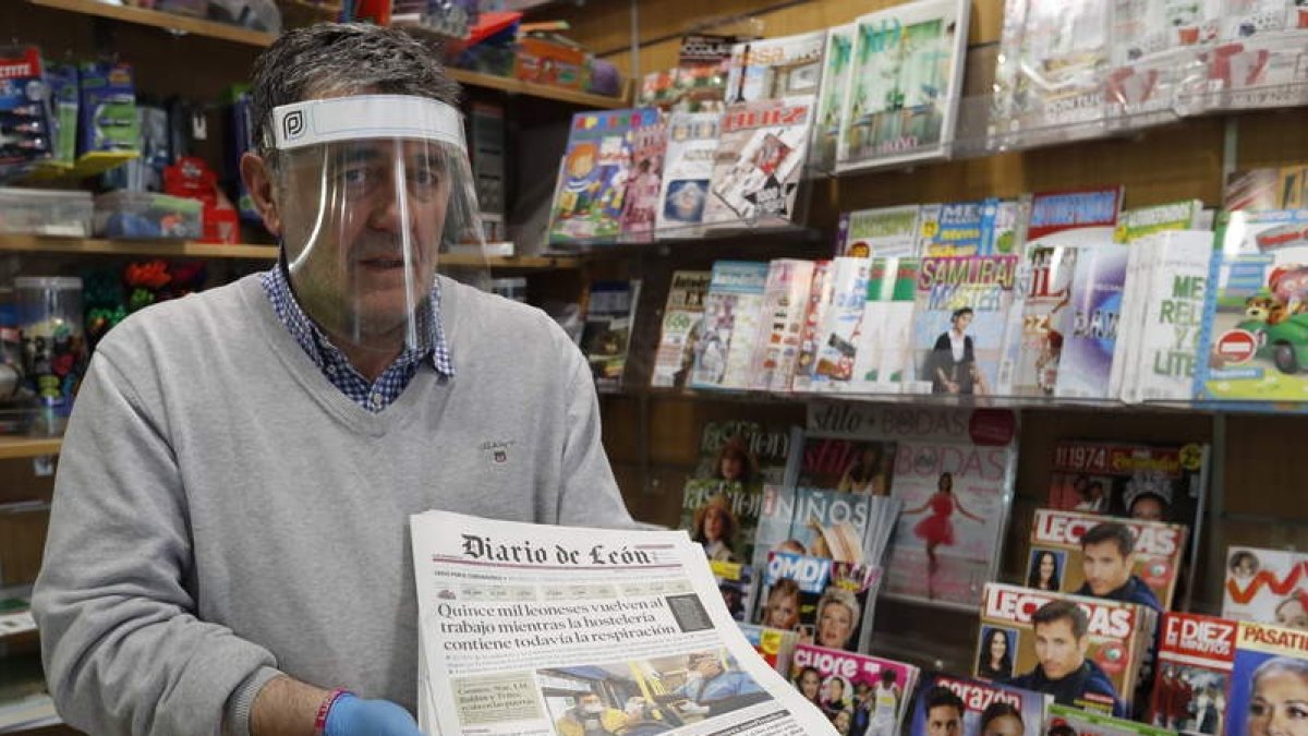 Marcos Garía, presidente de la Asociación de Vendedores de Prensa, sostiene un Diario de León en su kiosco. RAMIRO