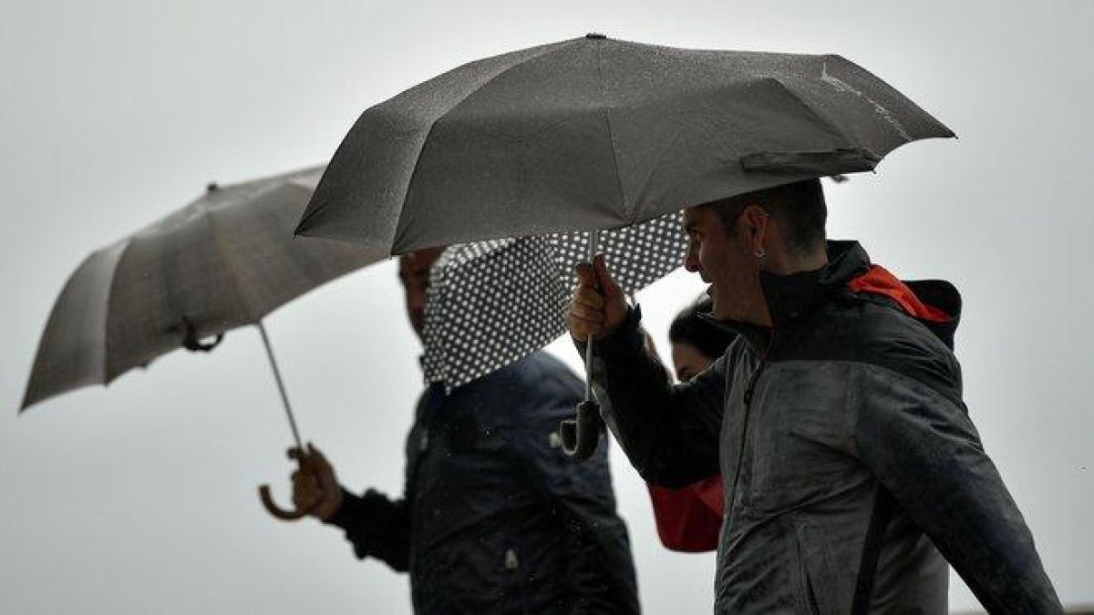 Unas personas se protegen de la lluvia.