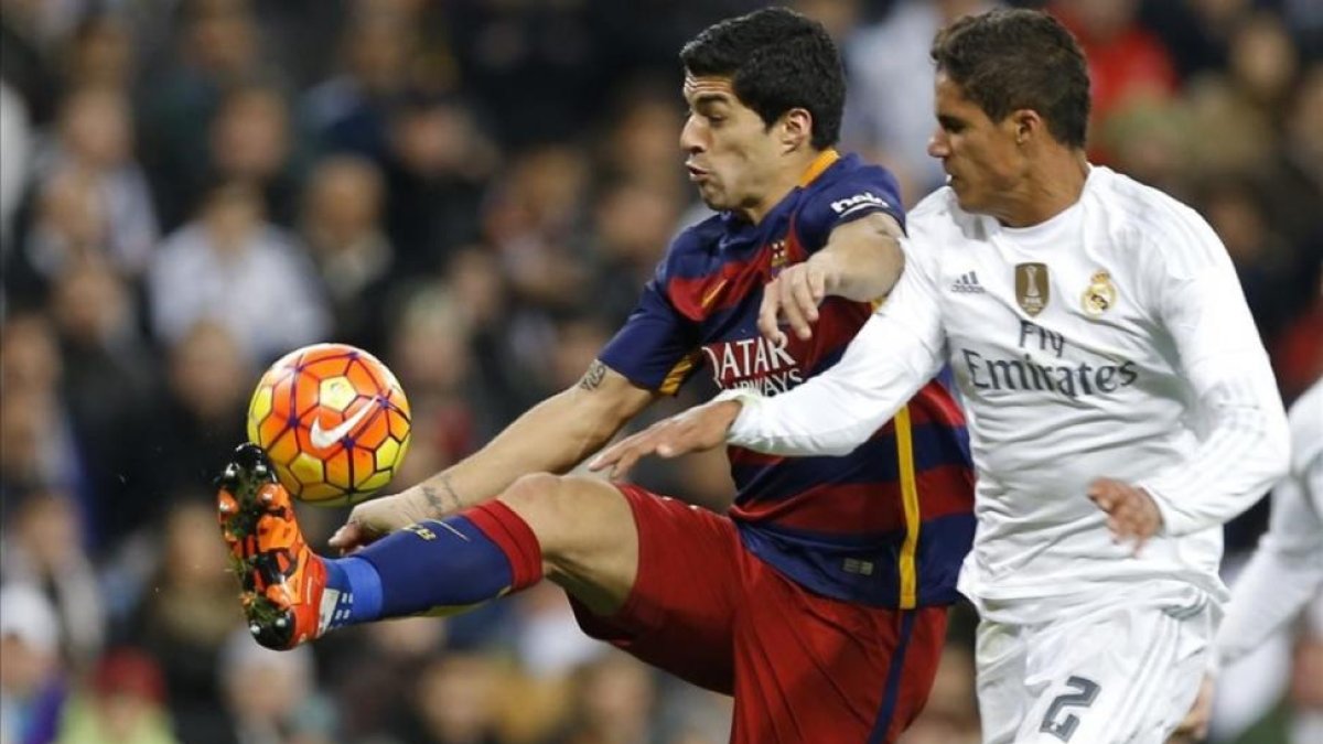 Varane y Luis Suárez luchan por un balón en el clásico del pasado año en el Bernabeú.