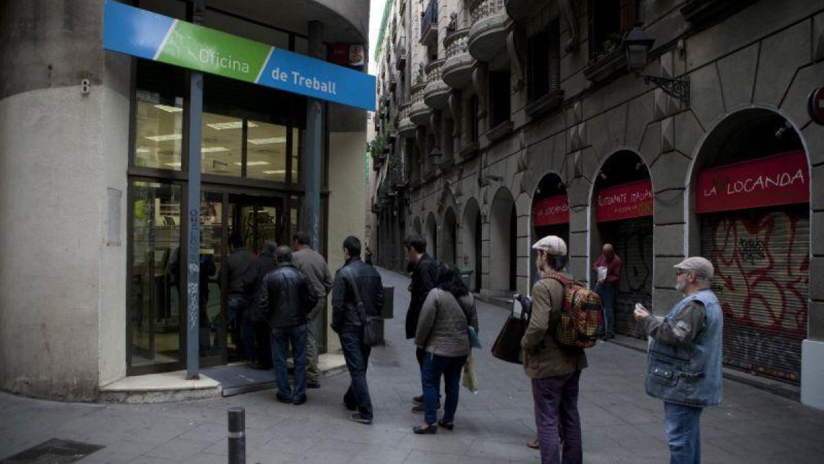 Varias personas haciendo cola frente a una oficina del Servei dOcupació de Catalunya (SOC).