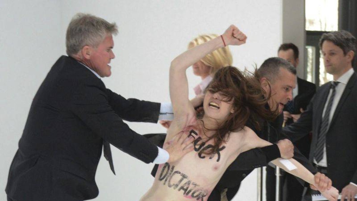 Personal de seguridad detienen a una activista de Femen que irrumpió en topless durante la visita del presidente ruso.