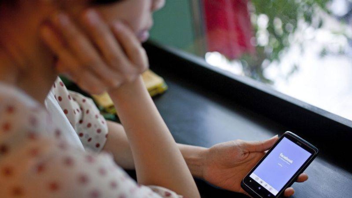 Una mujer accede a Facebook desde su teléfono móvil.