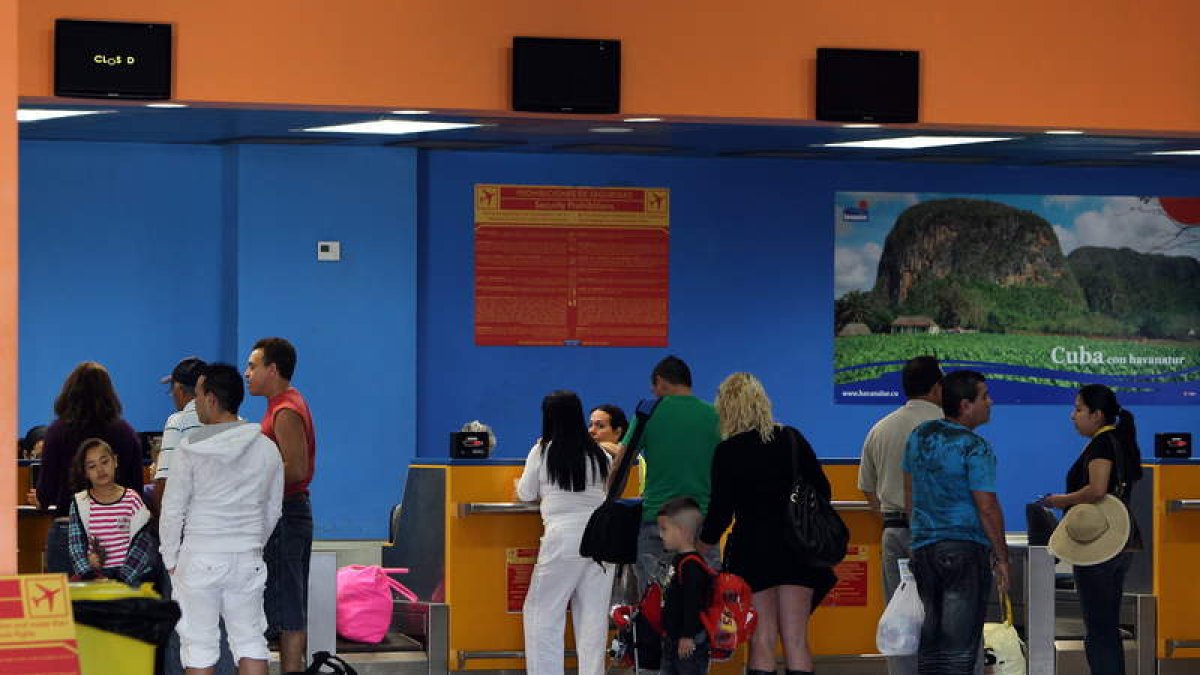 Varias personas chequean sus documentos para abordar un vuelo hacia Miami.