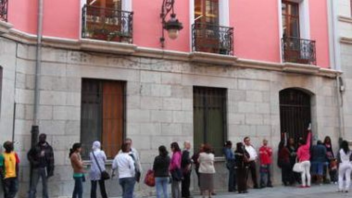 Personas que aguardaban ayer en la cola para solicitar ayuda en la nueva sede de Cáritas León, en la
