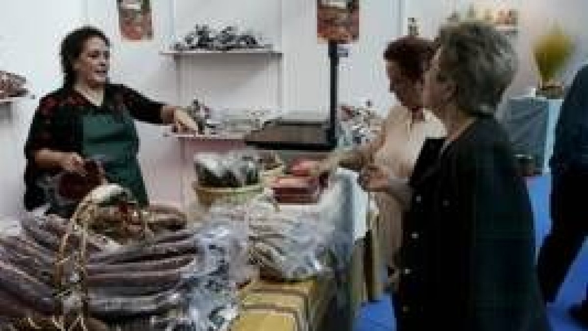 Unas de las primeras clientas de la feria compra en uno de los numerosos expositores de embutidos