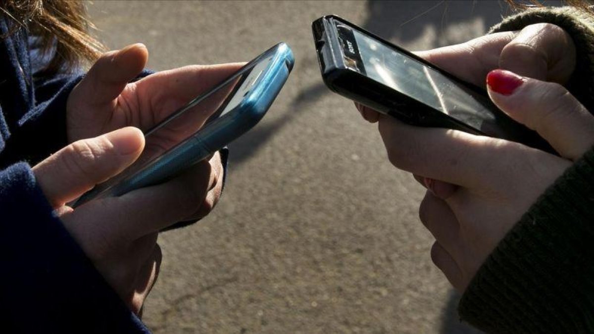 Unas jóvenes establecen contactos a través del móvil.