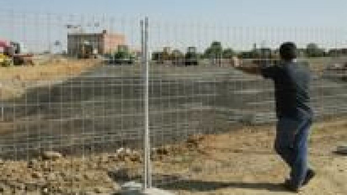 Un hombre observa las obras de la polémica detrás de la valla protectora