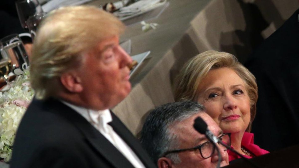 Clinton, sentada junto al obispo de Nueva York, observa a Trump durante su intervención en la cena benéfica del jueves.