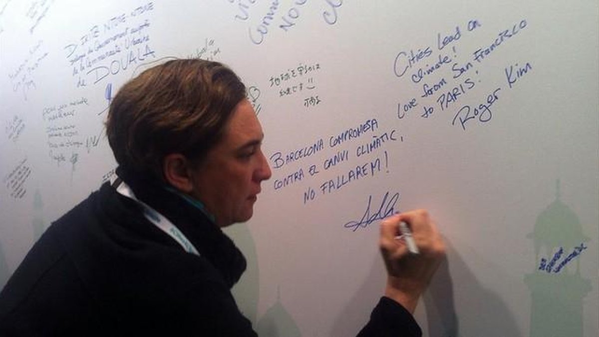 Colau firma en una pizarra su compromiso contra el cambio climático, en París, este viernes.