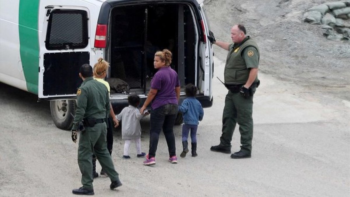 Oficiales migratorios de los EEUU detienen a una mujer y sus hijos.