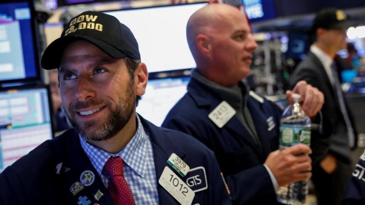 Un operdor de la Bolsa de Nueva York con una gorra conmemorativa de los 23.000 puntos alcanzados.